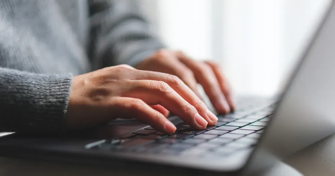 Hands typing on laptop