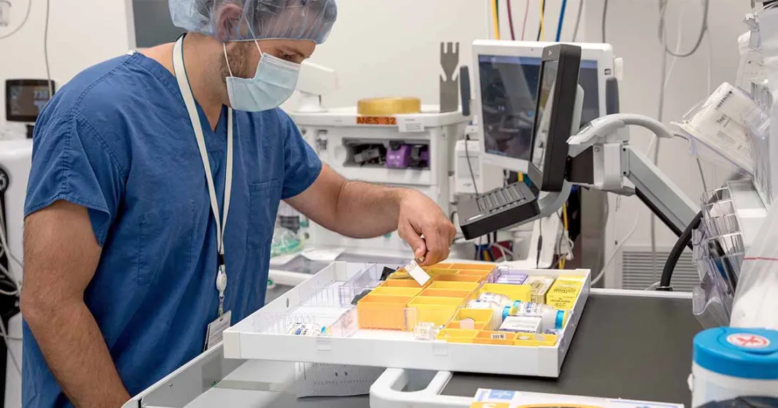 Lab worker in scrubs and mask sorting medication