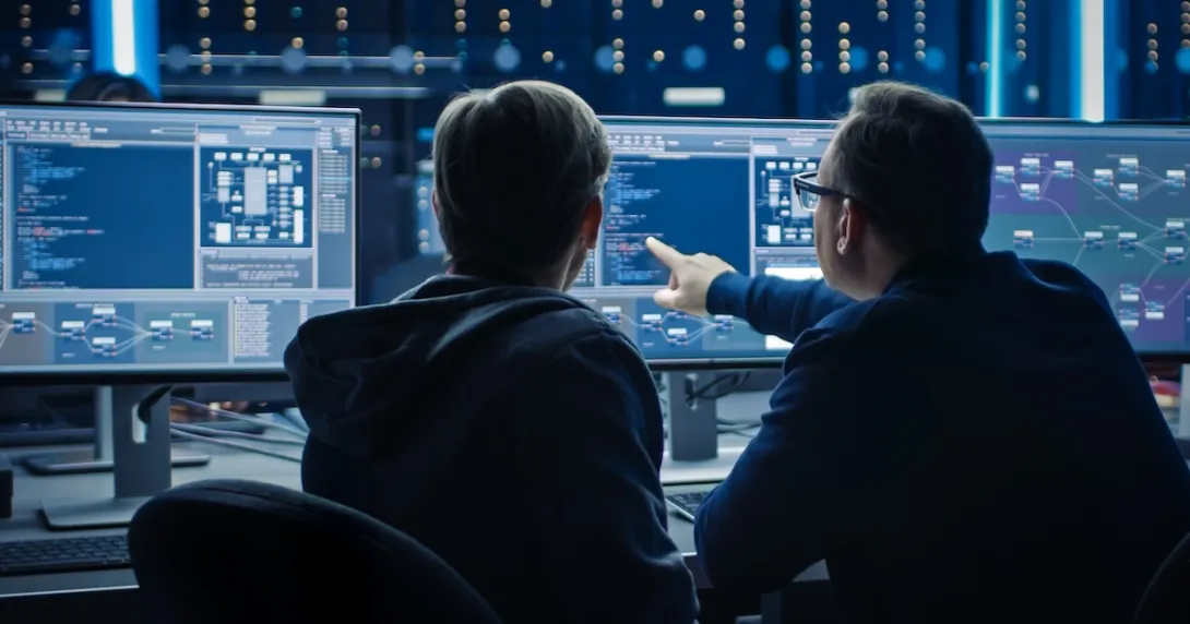 Two computer programmers working on code in desktop computers