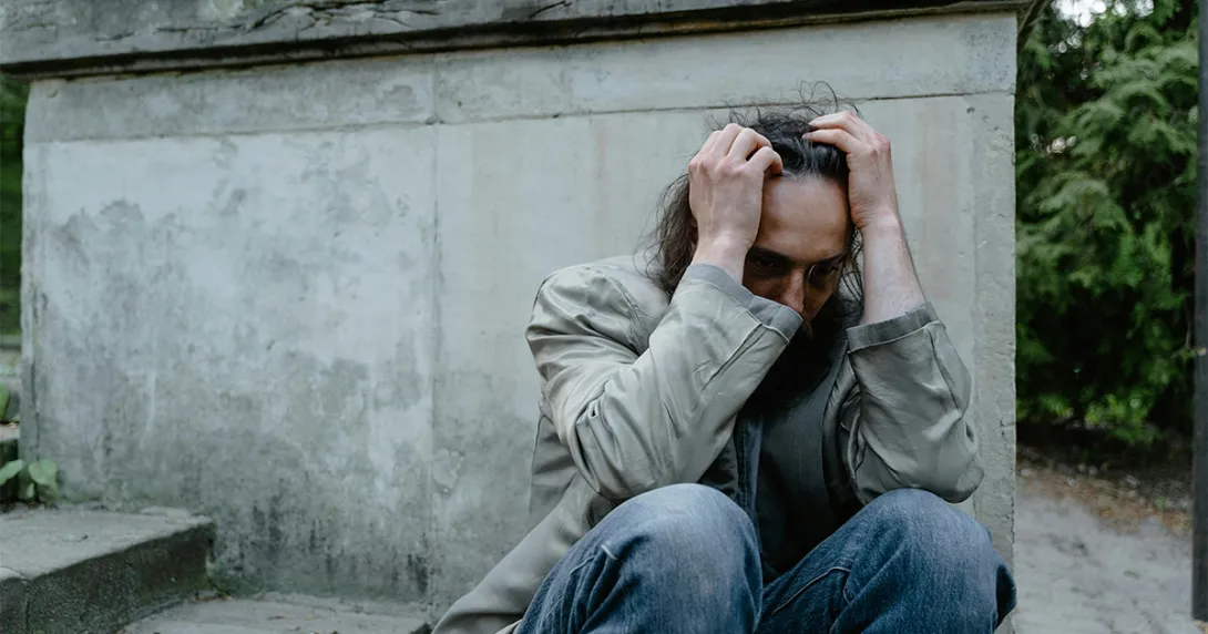 Homeless man holds head