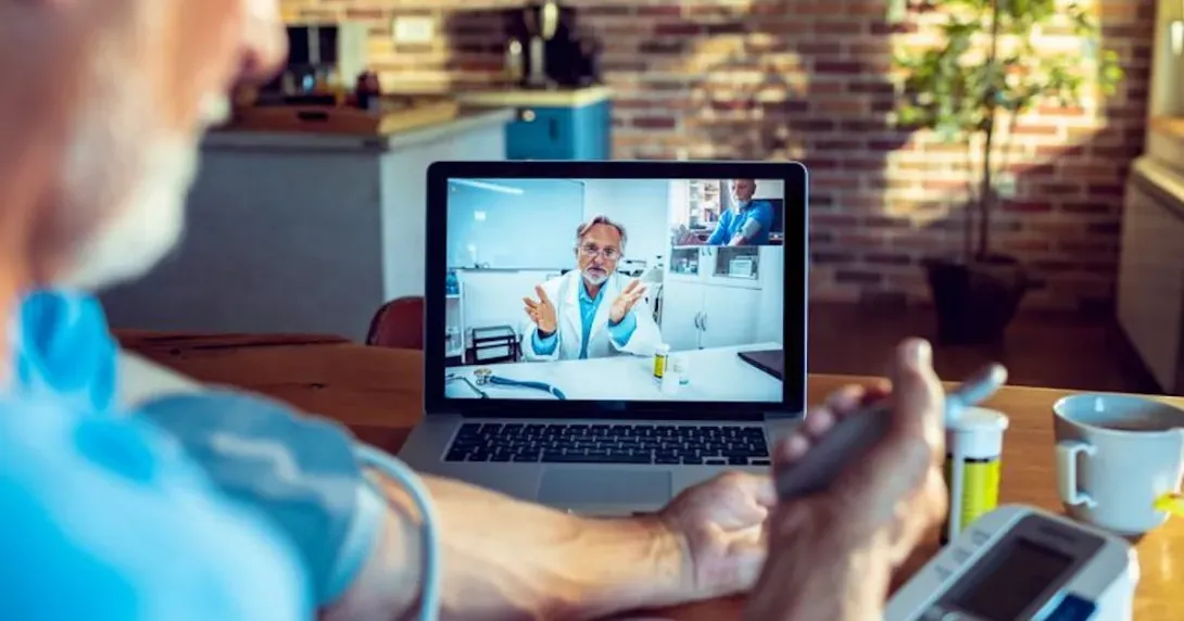 Cardiology patient checks his blood pressure during a telehealth call with his doctor