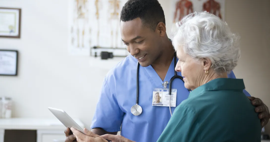 A nurse assisting an elderly patient with using a digital tablet
