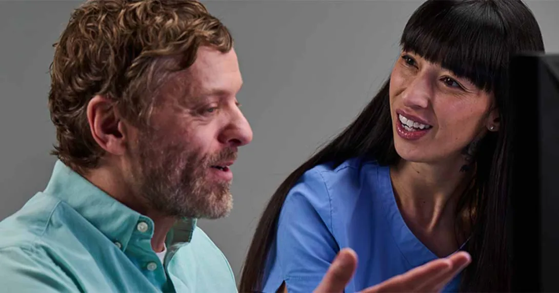 People talking in front of a computer monitor