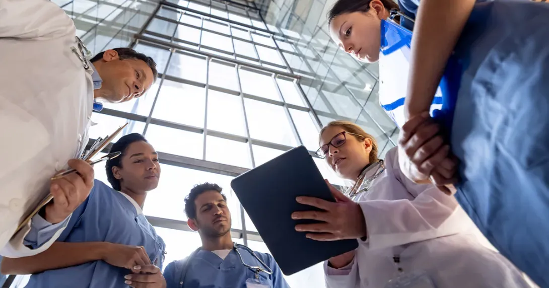 Healthcare team gathers to look at data on a tablet