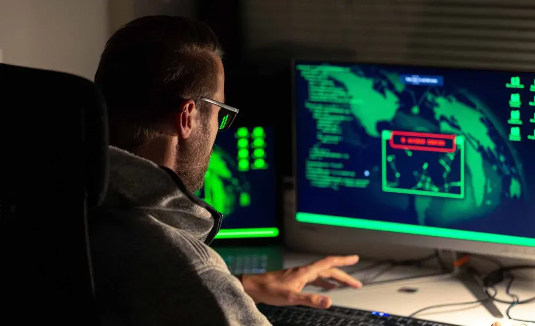 Hacker reviews a map on a monitor