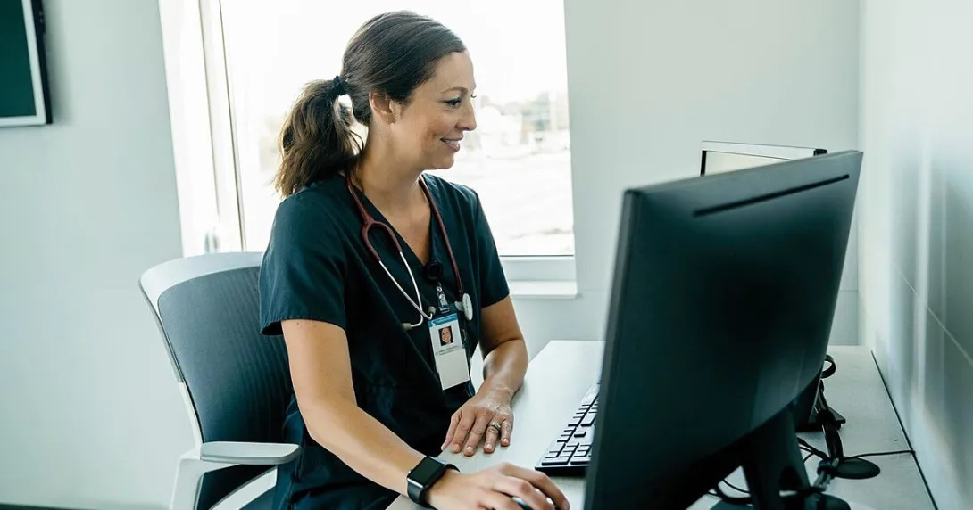 A doctor reviewing a patient record on a desktop computer