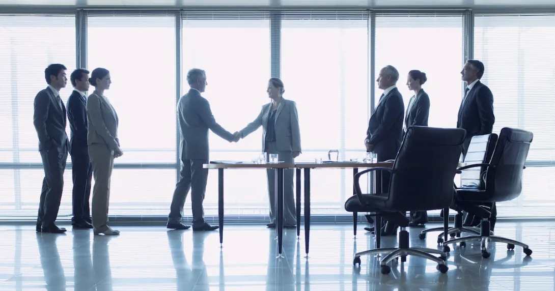 Officials in suits shake hand in closing a deal