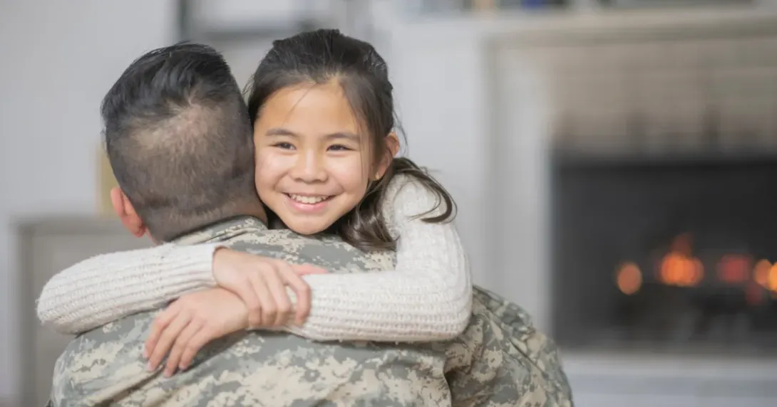 Army service member hugs child