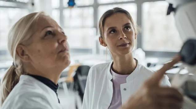 Two healthcare workers looking up at a monitor