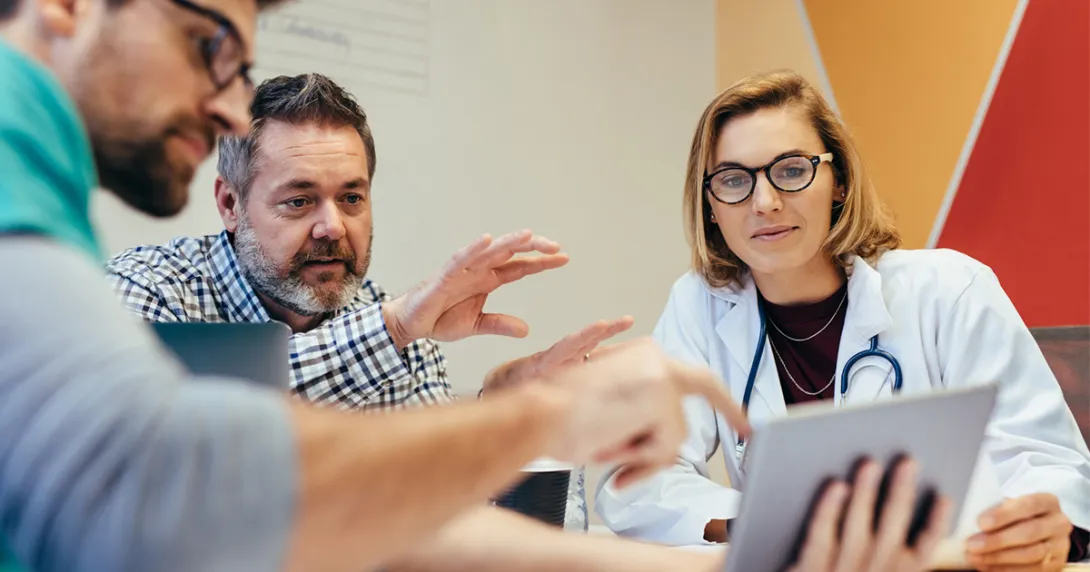 Doctor meeting with businesspeople and looking at a tablet