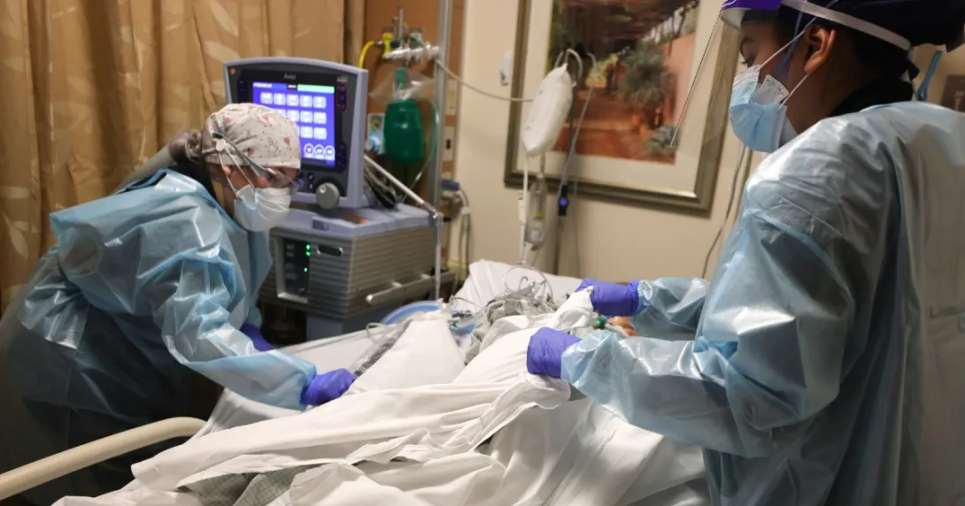 Clinicians in protective gear take care of an ICU patient.