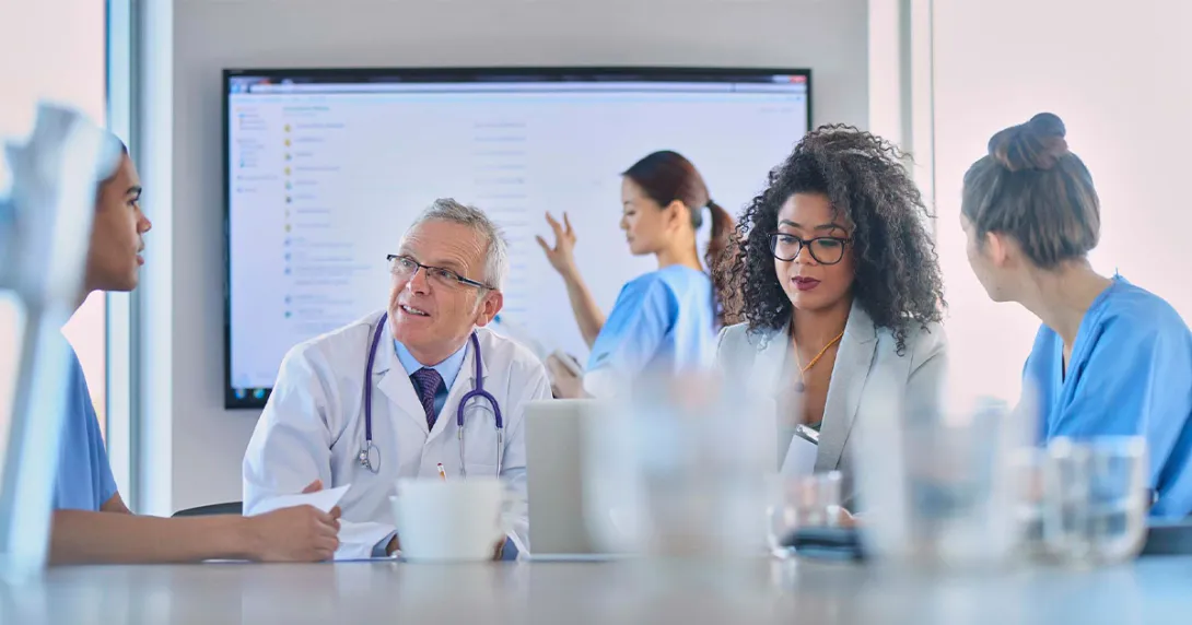 Healthcare workers meeting with large screen in background