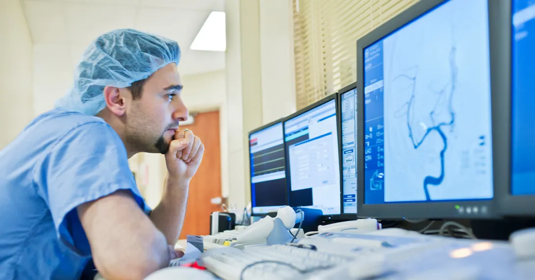 Healthcare worker in scrubs looking at medical image on screen