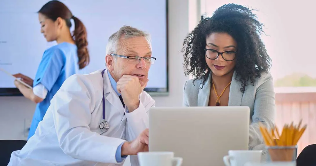 Doctor and businessperson looking at laptop screen