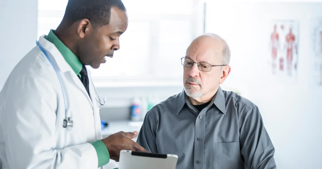 A doctor shows a patient some information on a tablet.