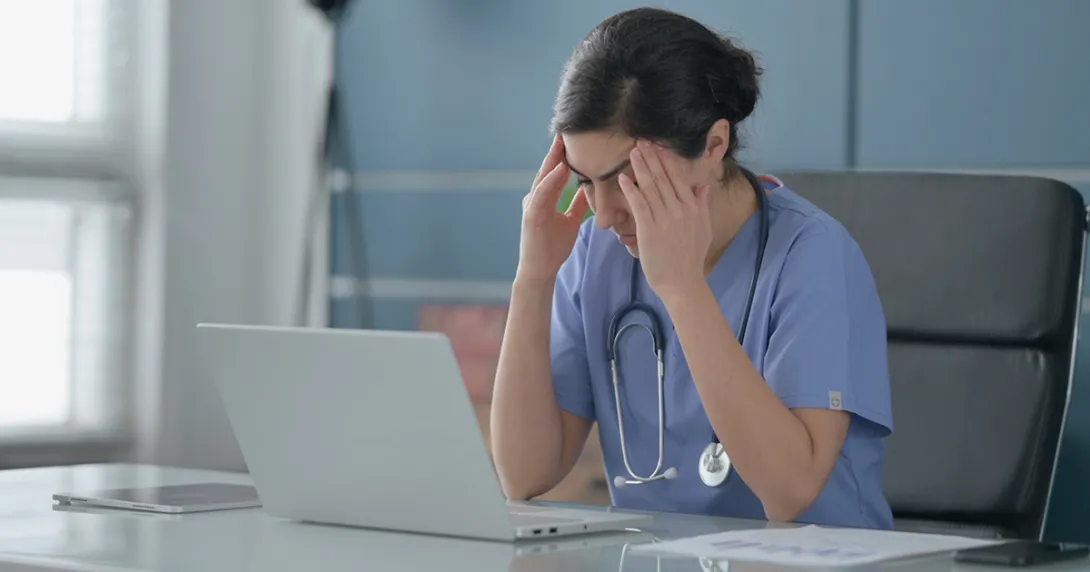 Frustrated physician documenting at laptop