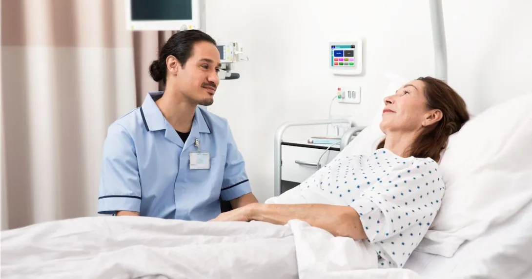 A nurse sitting beside a patient in bed