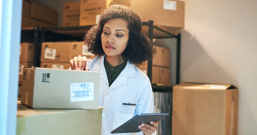 A pharmacist using a digital tablet while doing inventory in the pharmacy stockroom