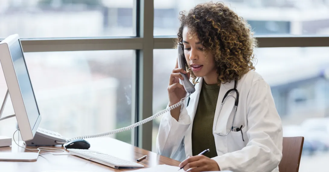 A doctor using a landline to make a phone call
