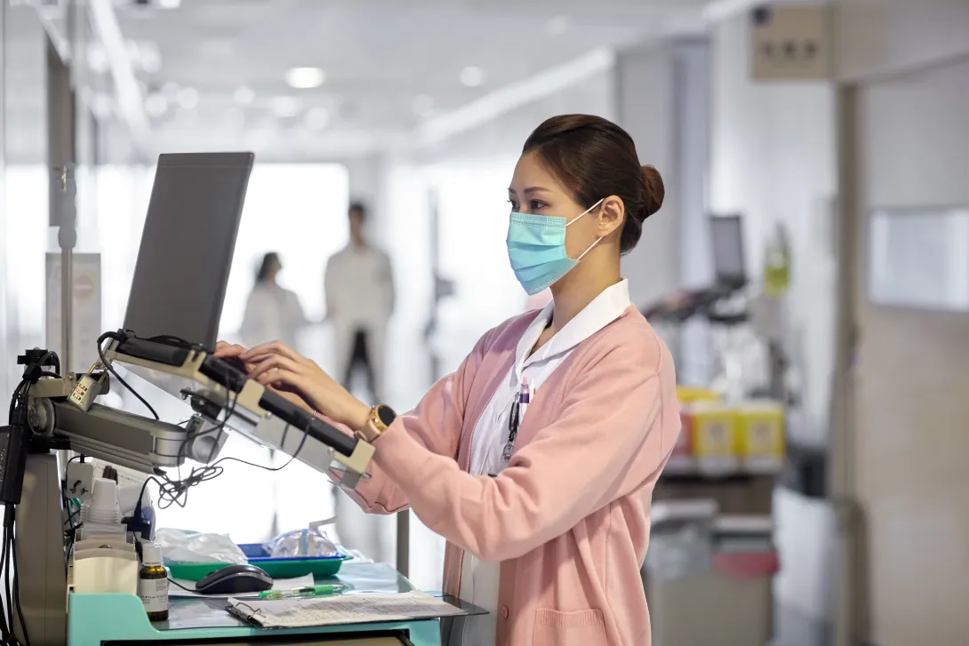 A nurse using a laptop to work on a medical report
