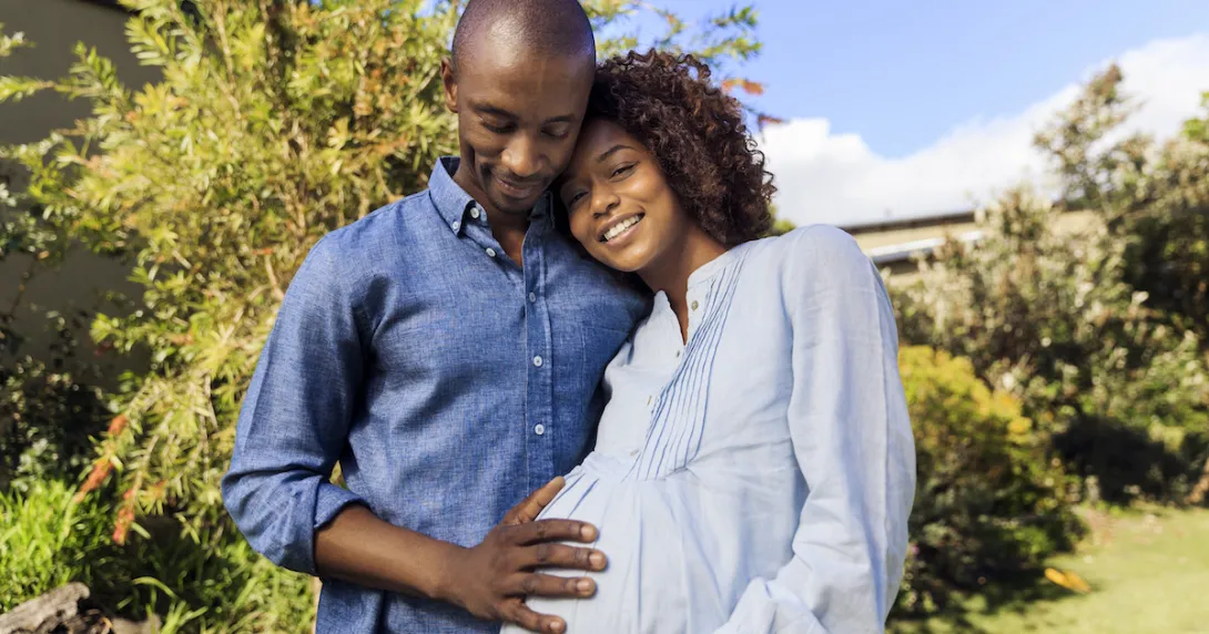 Pregnant person and partner embracing