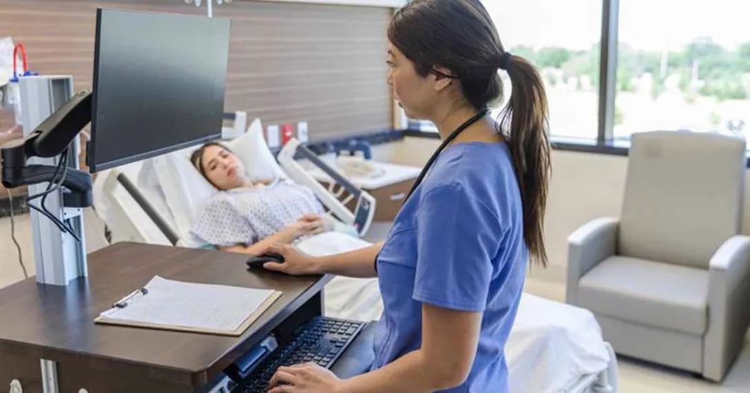 Nursing using laptop in hospital room with patient