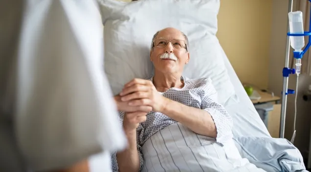 patient in hospital bed holding person's hand