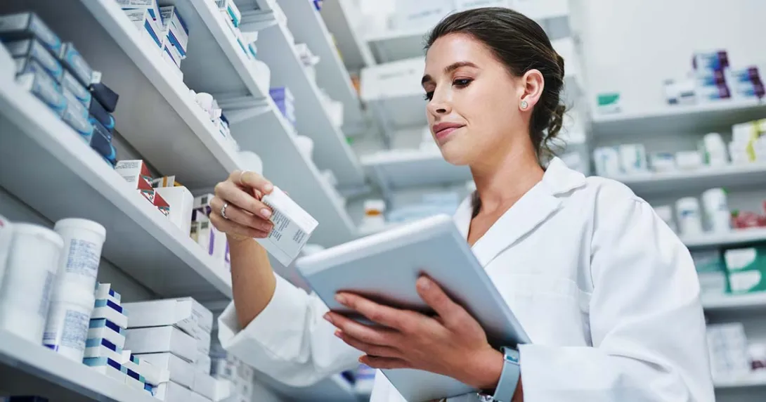 Pharmacist with a tablet looking at a medication box