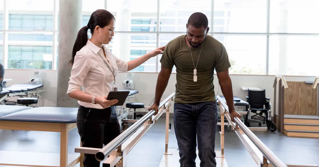 Physical therapist helping patient walk