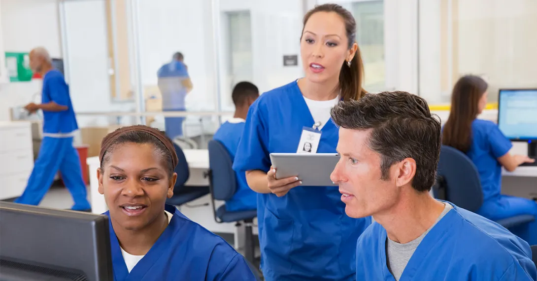 Nurses talking while looking at computer screen