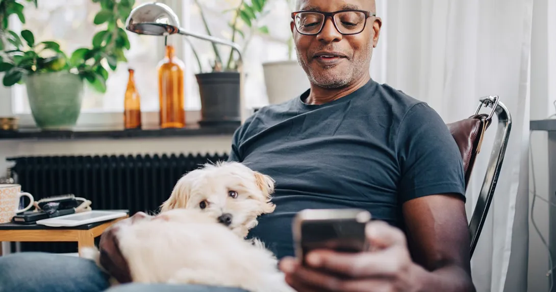 Man with his dog sitting at home having a mobile call with a care team member