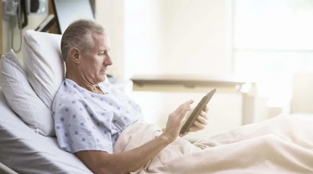 Patient using tablet in hospital bed