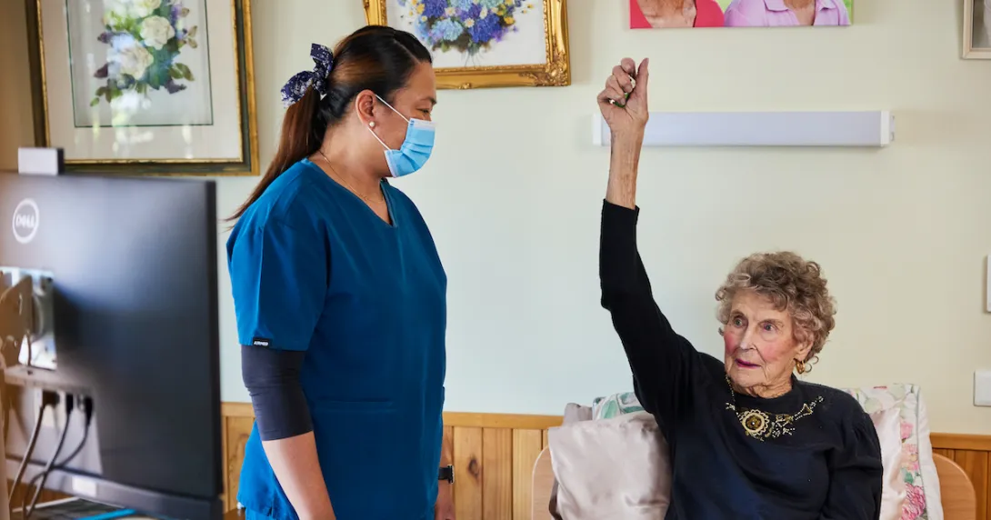 An iAgeHealth nurse assisting a senior patient at home with their virtual checkup