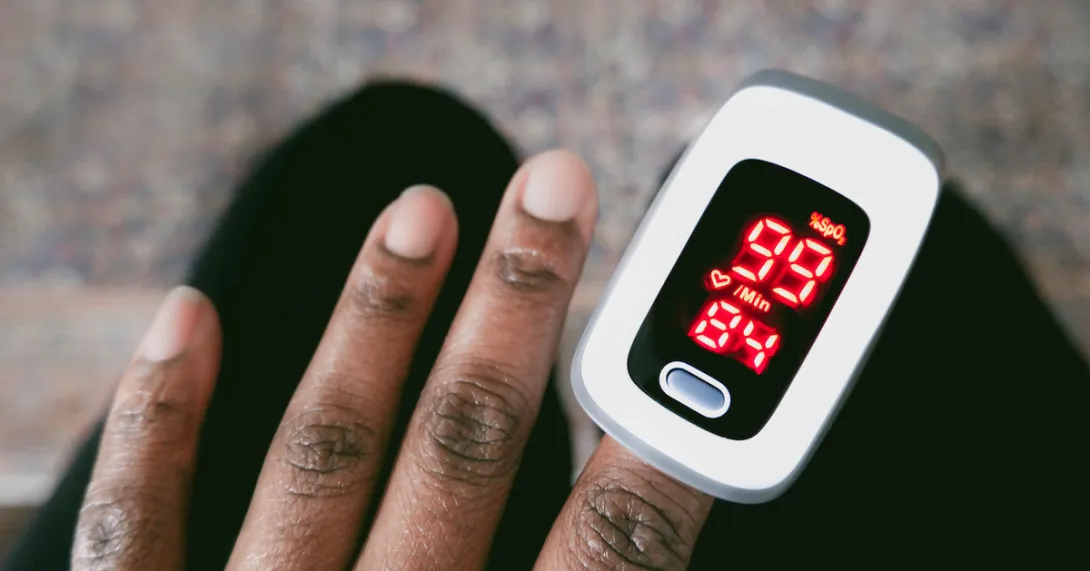 Dark skinned hand with a pulse oximeter measuring the patient's oxygen levels