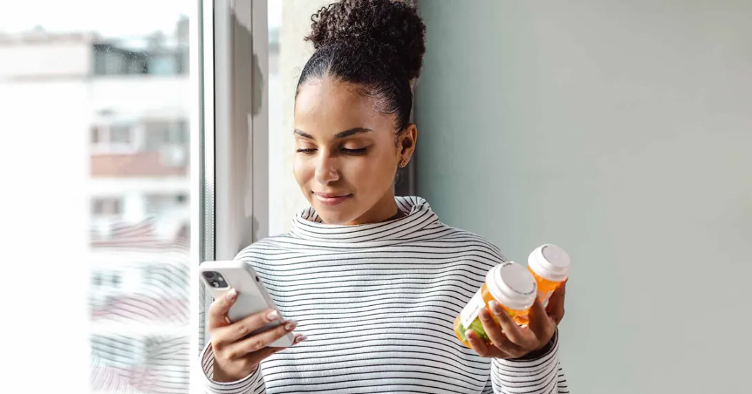Person holding pill bottles and phone
