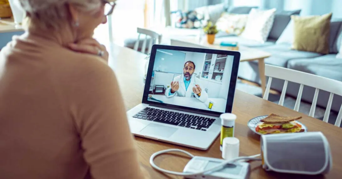 Cardiac patient talking to cardiologist on a telehealth call with monitor, medication and a sandwich on the table