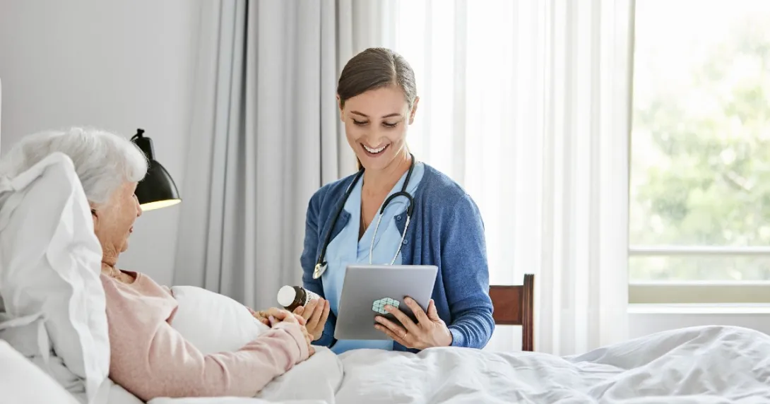 caregiver at patient bedside reviews prescription information with a virtual care prescriber on a tablet