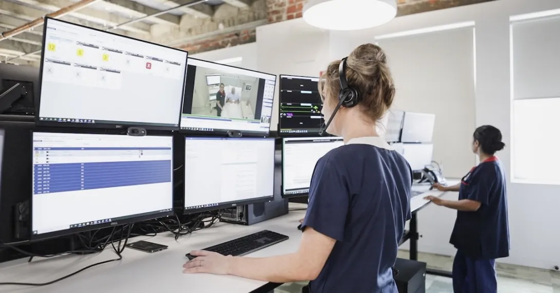 Two people standing before a bank of screens