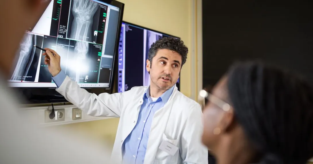 Radiologist points to image on screen during a consultation with fellow clinicians