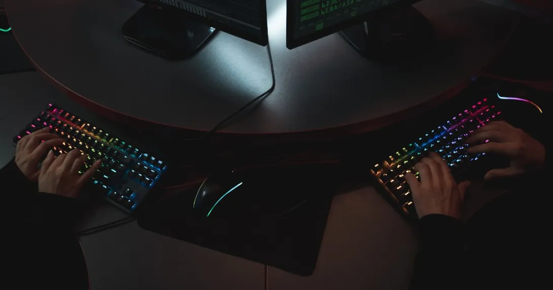 Two hackers side by side with hands on keyboards