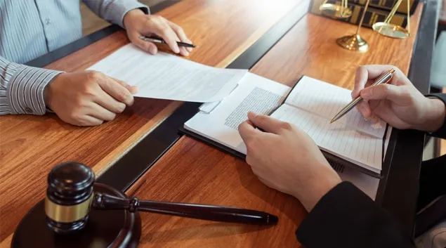 Two people reviewing documents with a gavel nearby