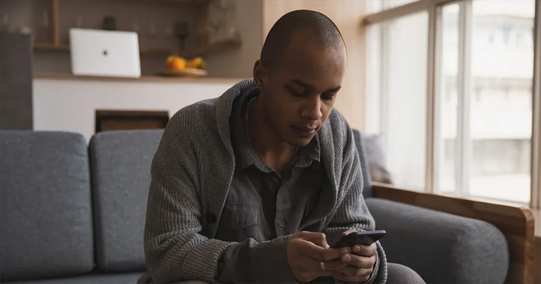 Man in gray on gray couch checks health records on a smartphone