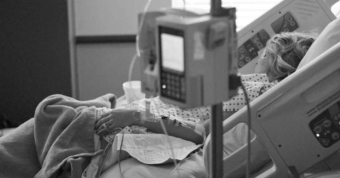 Woman asleep in hospital bed with IV in foreground