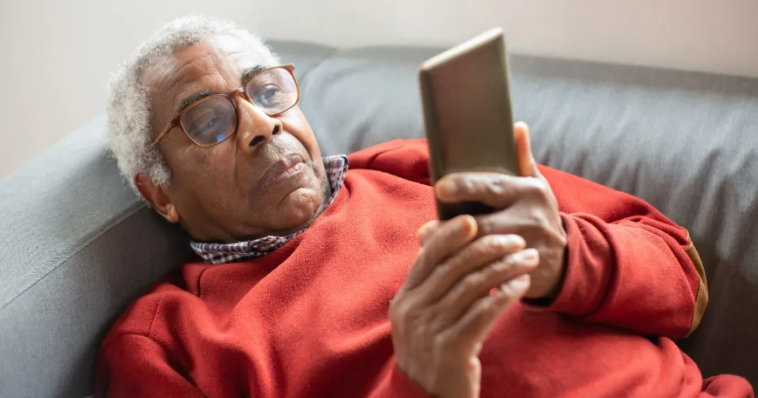 Person lies on couch reading from mobile phone
