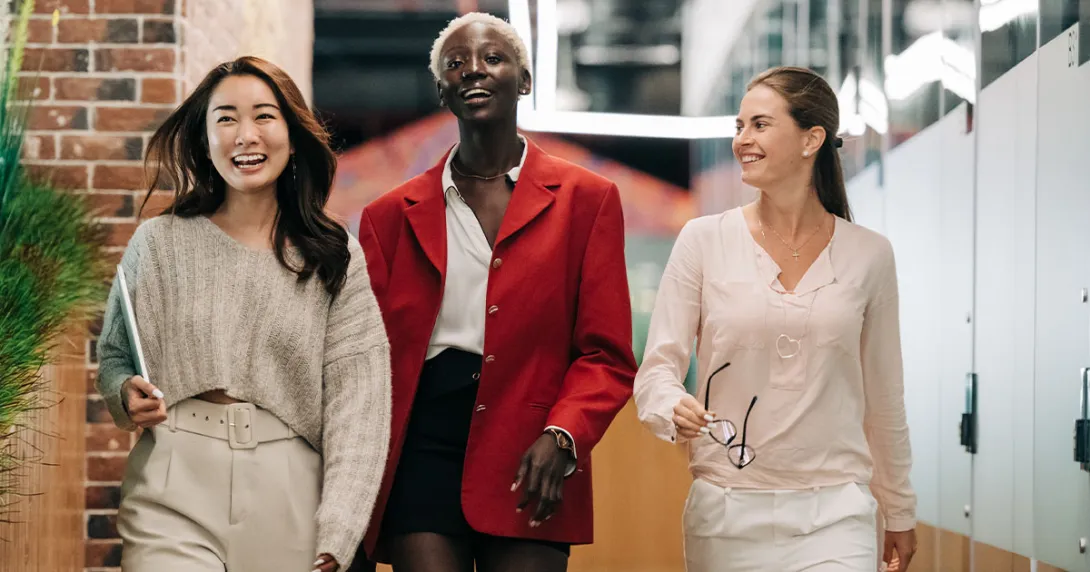 Three people walk toward the camera in an office setting.