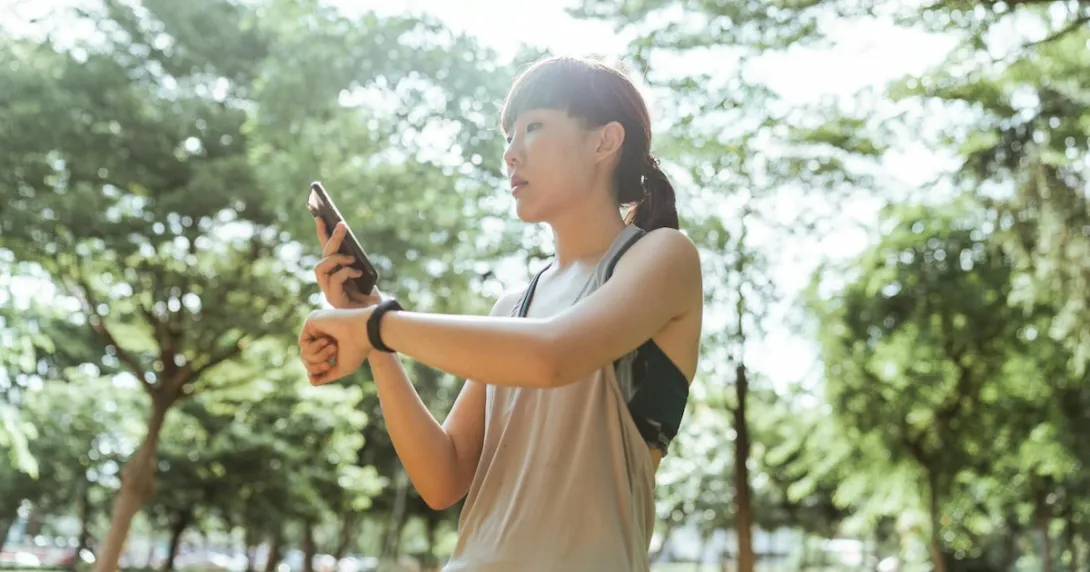 A person checking their smartwatch-tracked fitness data on their smartphone.