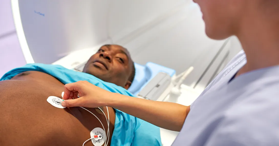 Technician puts ECG stickers on the chest of personabout to enter an MRI machine