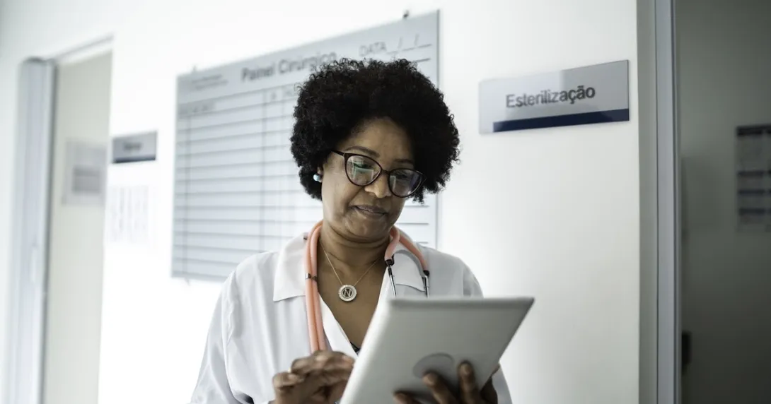 Female doctor reviews information on a tablet in a hallway