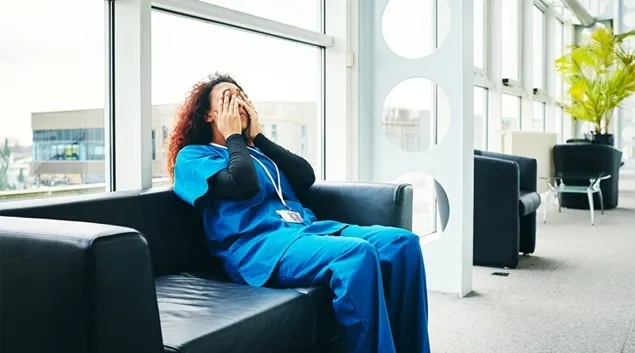 Healthcare worker sitting and rubbing their eyes