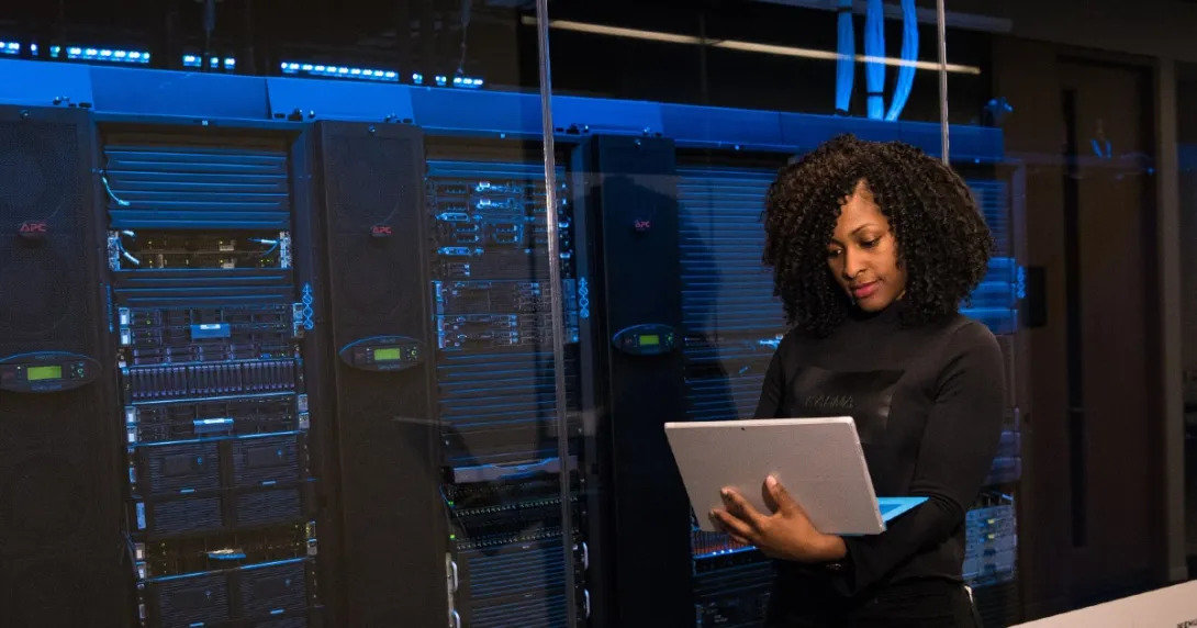 HIT professional reviews information on a laptop outside a server room